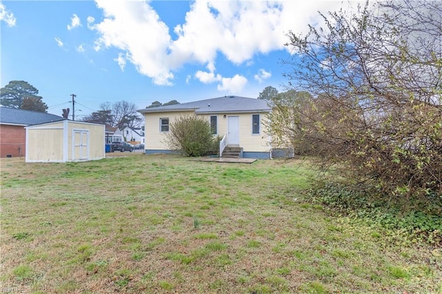 rear view of property with a yard and a storage unit