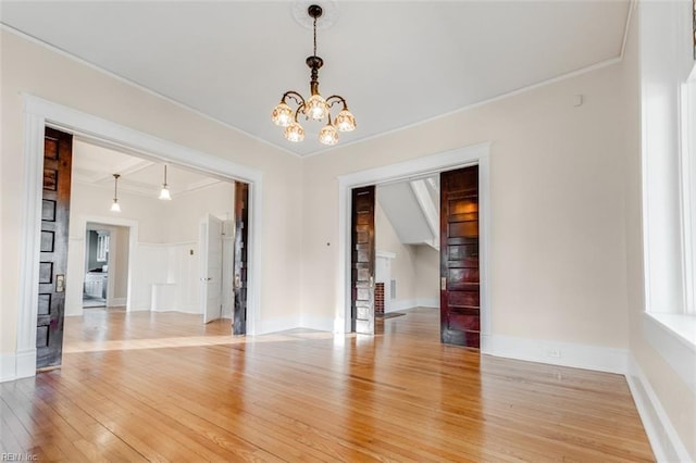 spare room with a notable chandelier, hardwood / wood-style flooring, and ornamental molding