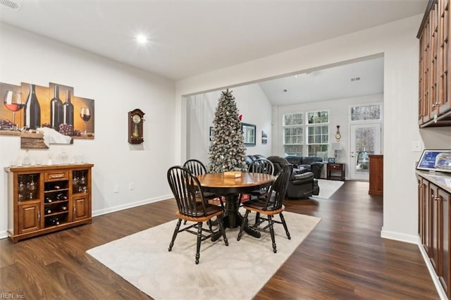 dining area featuring dark hardwood / wood-style floors and vaulted ceiling