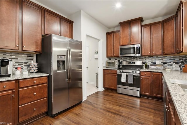 kitchen featuring light stone counters, dark wood-type flooring, stainless steel appliances, and tasteful backsplash