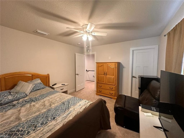 bedroom featuring light carpet, ceiling fan, and a textured ceiling