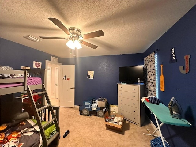 carpeted bedroom with ceiling fan and a textured ceiling