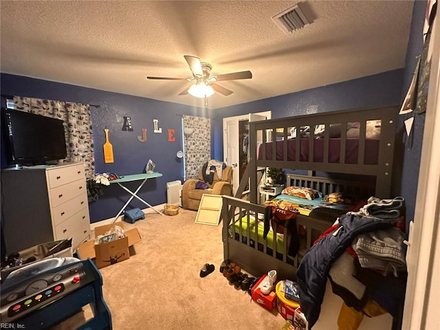 bedroom with ceiling fan, carpet flooring, and a textured ceiling