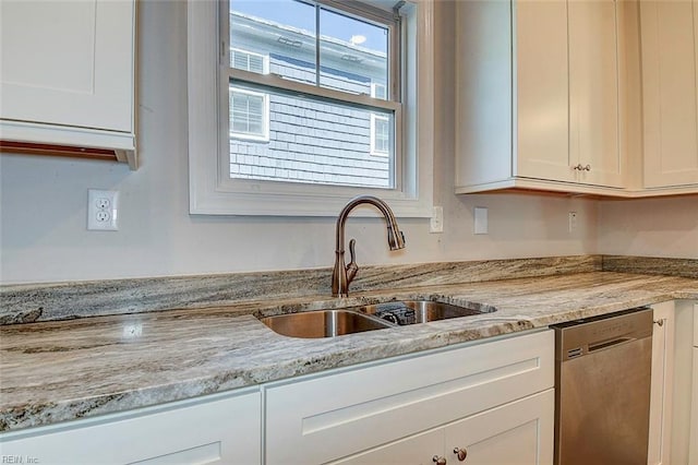 kitchen featuring white cabinetry, sink, stainless steel dishwasher, and light stone countertops