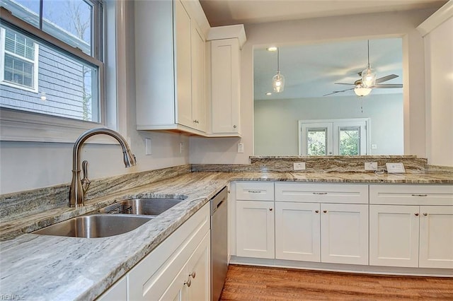 kitchen with sink, dishwasher, ceiling fan, white cabinetry, and light stone counters