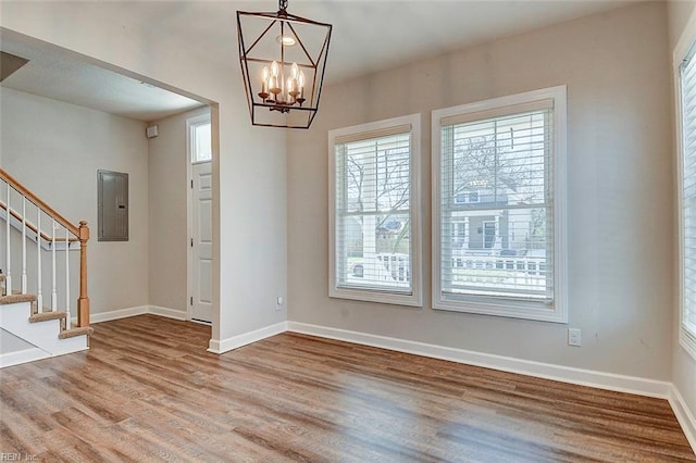 interior space with an inviting chandelier, electric panel, and light hardwood / wood-style flooring