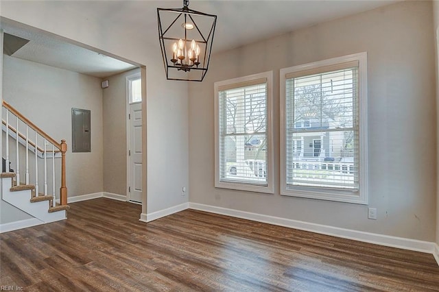 interior space with an inviting chandelier, electric panel, and dark hardwood / wood-style floors