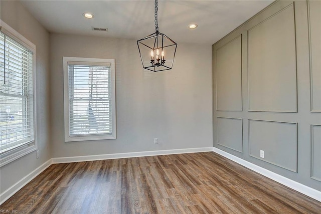 unfurnished dining area featuring an inviting chandelier and hardwood / wood-style flooring