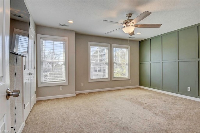 empty room featuring ceiling fan, light colored carpet, and a textured ceiling