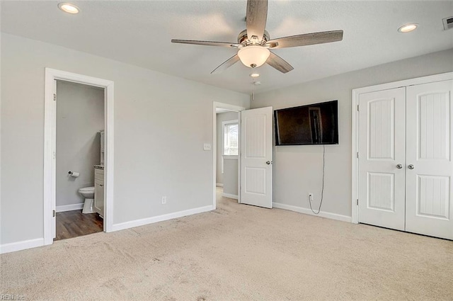 unfurnished bedroom featuring ceiling fan, light carpet, ensuite bath, and a closet