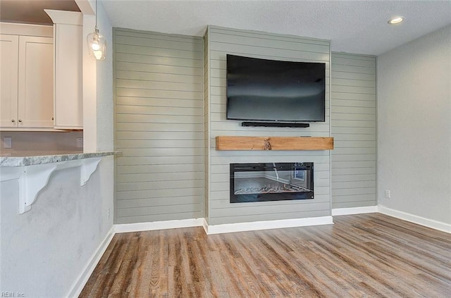 unfurnished living room with a fireplace, light hardwood / wood-style flooring, and wood walls