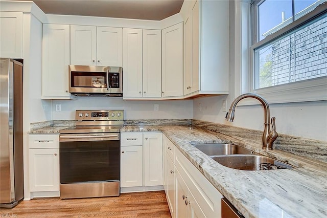 kitchen featuring white cabinetry, appliances with stainless steel finishes, sink, and light stone counters