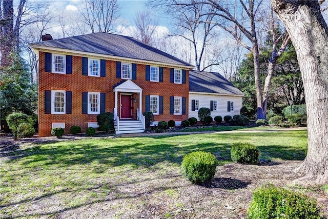 colonial inspired home featuring crawl space, brick siding, a chimney, and a front yard