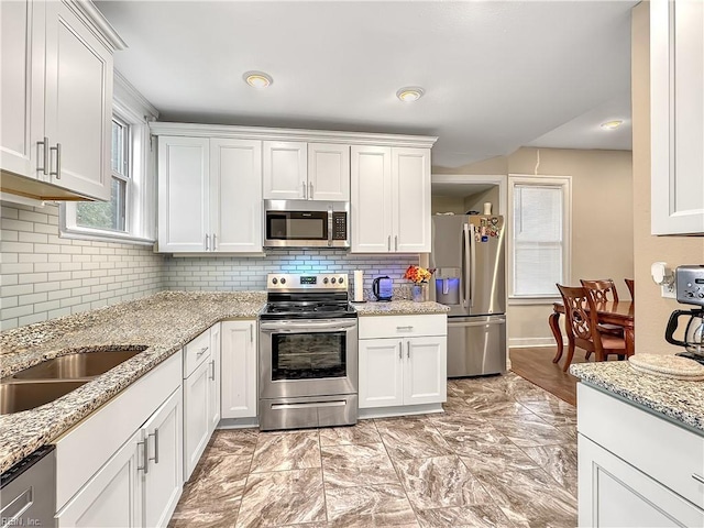 kitchen with white cabinetry, light stone counters, tasteful backsplash, and appliances with stainless steel finishes