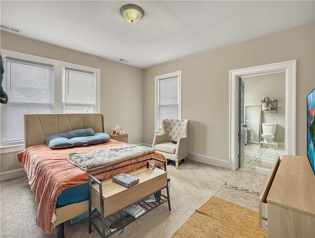 carpeted bedroom with ensuite bath and a textured ceiling