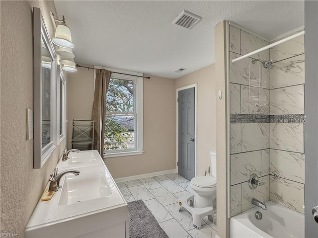 full bathroom featuring vanity, toilet, tiled shower / bath combo, and a textured ceiling