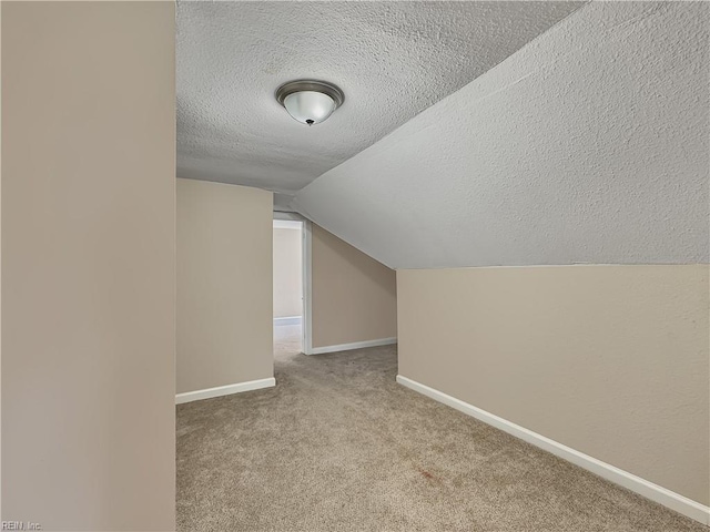 bonus room with lofted ceiling, light carpet, and a textured ceiling