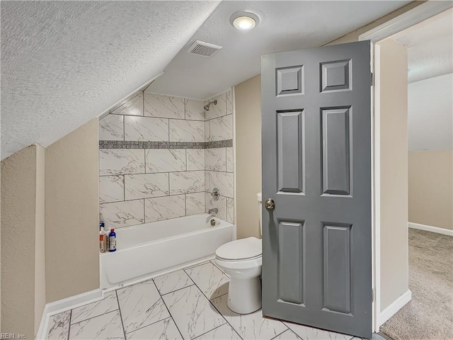 bathroom featuring tiled shower / bath, toilet, and a textured ceiling