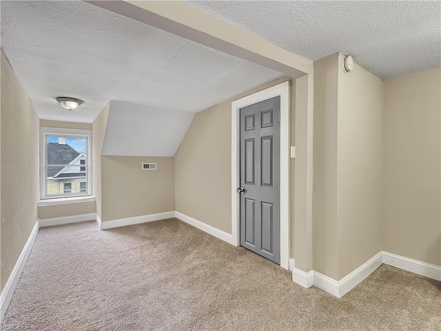 bonus room featuring carpet flooring and a textured ceiling