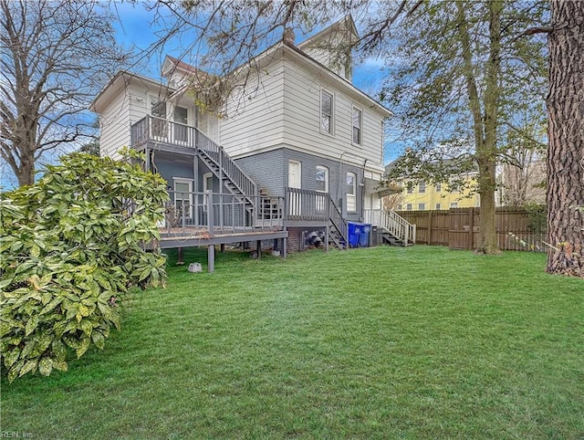 rear view of property with a yard, a balcony, and a deck