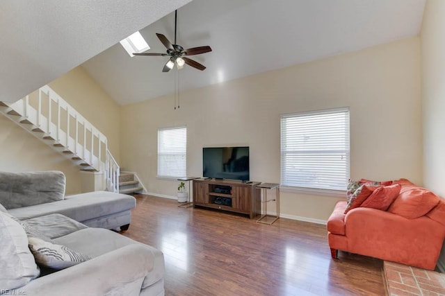 living room with high vaulted ceiling, dark hardwood / wood-style floors, ceiling fan, and a skylight