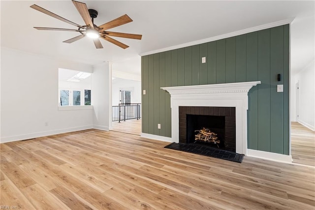 unfurnished living room with a brick fireplace, light hardwood / wood-style flooring, ornamental molding, and ceiling fan