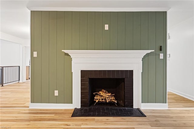 details featuring a brick fireplace, crown molding, and hardwood / wood-style flooring