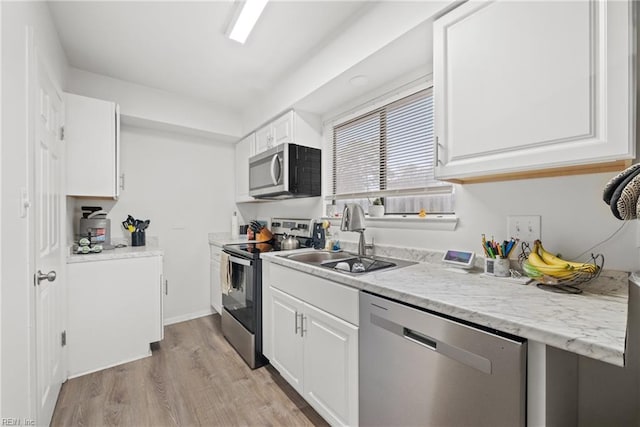 kitchen with sink, stainless steel appliances, light stone countertops, light hardwood / wood-style floors, and white cabinets