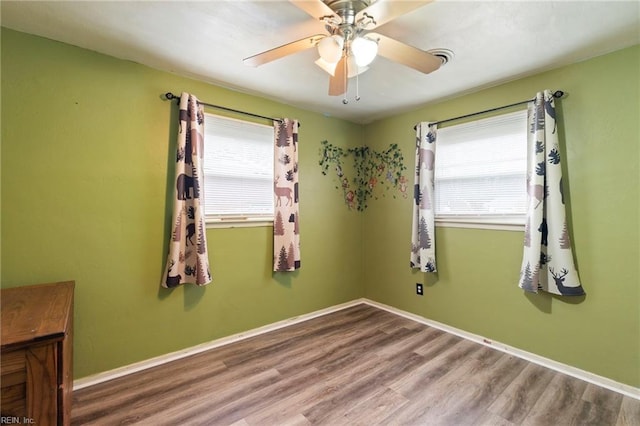 empty room with ceiling fan, a healthy amount of sunlight, and hardwood / wood-style floors