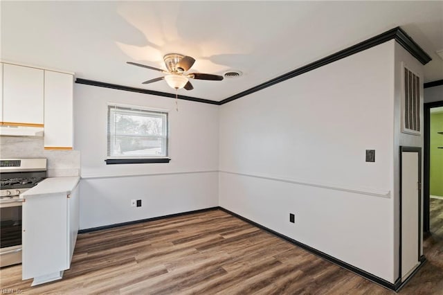 kitchen with white cabinetry, dark hardwood / wood-style flooring, stainless steel gas range, and crown molding