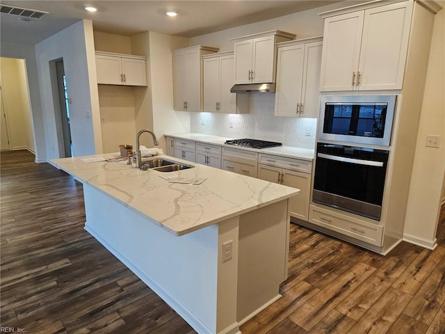 kitchen featuring built in microwave, a kitchen island with sink, sink, and wall oven