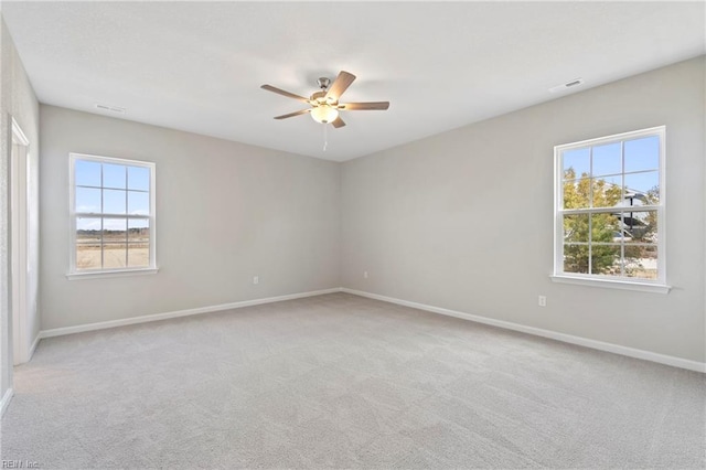 carpeted spare room with ceiling fan and a wealth of natural light