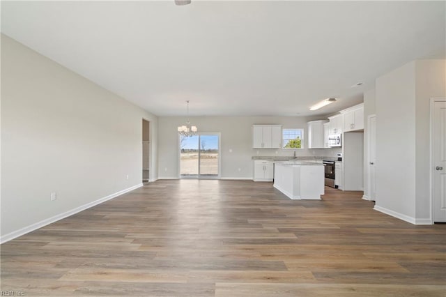 unfurnished living room with an inviting chandelier and light wood-type flooring