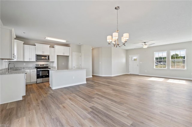 kitchen featuring decorative light fixtures, white cabinets, a center island, stainless steel appliances, and light hardwood / wood-style flooring