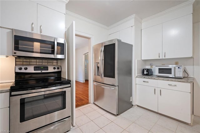 kitchen featuring light tile patterned flooring, ornamental molding, stainless steel appliances, and white cabinets