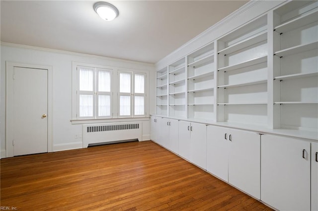 spare room with radiator, crown molding, and light wood-type flooring