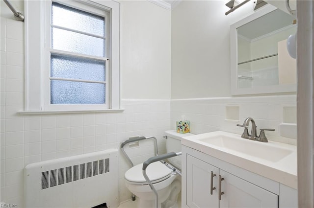 bathroom featuring vanity, toilet, radiator, and tile walls