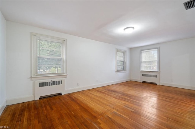 unfurnished room featuring hardwood / wood-style floors and radiator heating unit