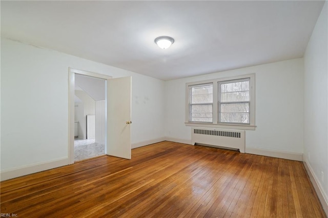 spare room with radiator heating unit and wood-type flooring