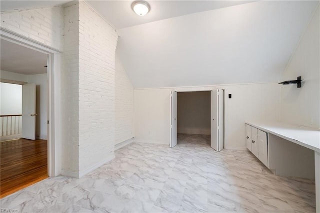 bathroom with brick wall and lofted ceiling