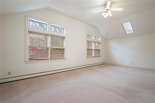 additional living space featuring ceiling fan, carpet floors, vaulted ceiling with skylight, and baseboard heating