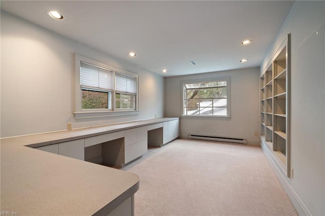 unfurnished office featuring baseboard heating, light colored carpet, and built in desk