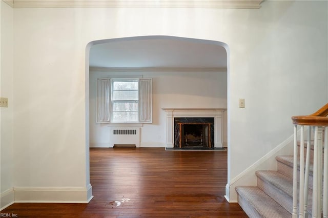 unfurnished living room with a premium fireplace, radiator, crown molding, and dark hardwood / wood-style floors