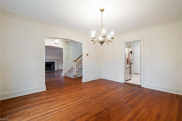 unfurnished room featuring hardwood / wood-style flooring, ornamental molding, and an inviting chandelier