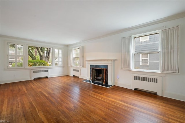 unfurnished living room with radiator heating unit, a fireplace, and wood-type flooring