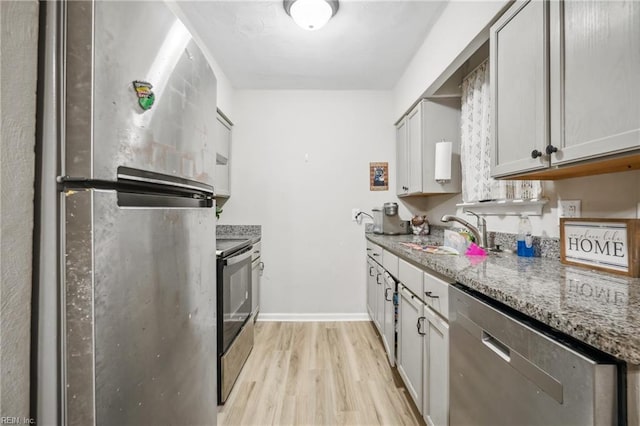 kitchen featuring light stone counters, sink, stainless steel appliances, and light wood-type flooring