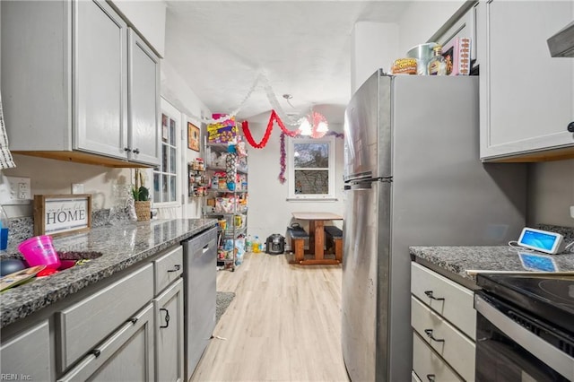 kitchen featuring dark stone countertops, gray cabinets, stainless steel appliances, and light wood-type flooring