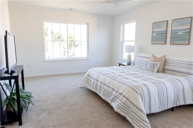 carpeted bedroom featuring multiple windows and ceiling fan