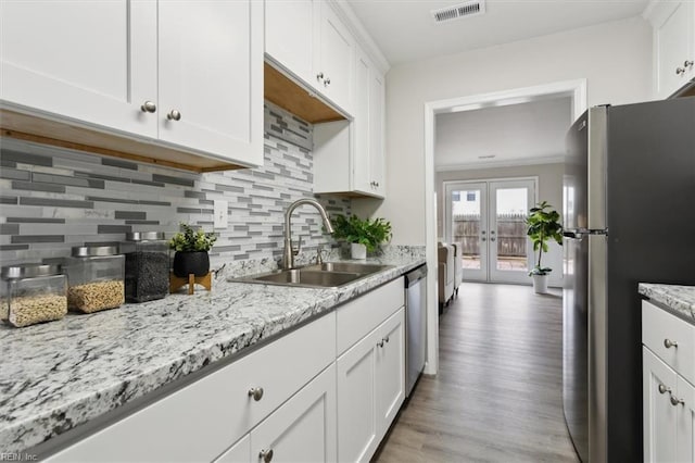 kitchen with french doors, sink, white cabinetry, light stone counters, and appliances with stainless steel finishes