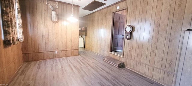 interior space with wood-type flooring, washer and dryer, and wooden walls